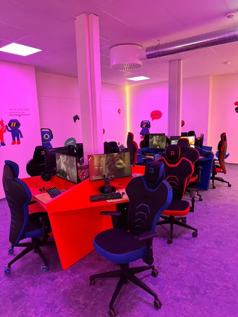 Spelstationer och sittplatser med rosa belysning på FUZED Borås