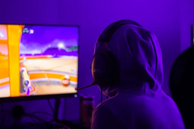En spelare med handkontroll i ett spelrum med lila belysning