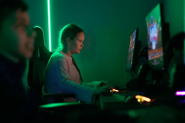 En ungdom som spelar vid en dator i grön belysning