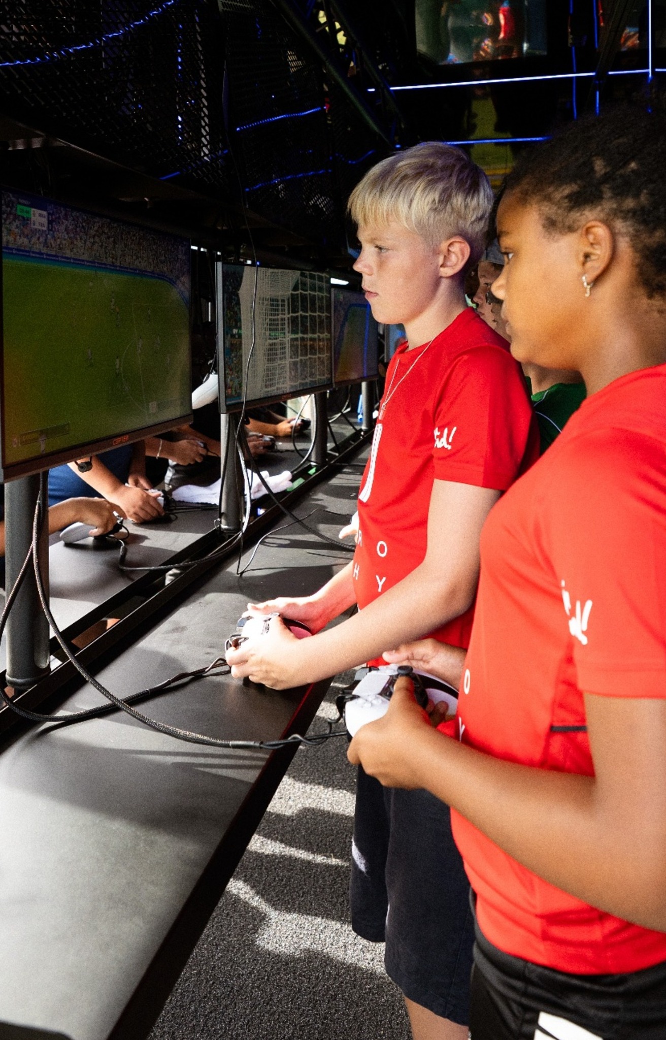 Unga spelare som tävlar i ett fotbollsspel med handkontroller