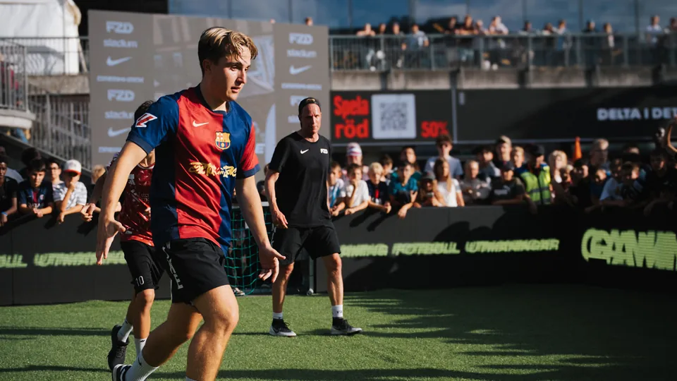 En ung fotbollsspelare på FUZED-planen med publiken som tittar på