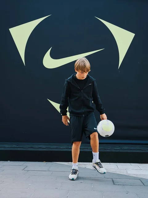 En ung deltagare som tränar bollkontroll framför Nike-bakgrunden