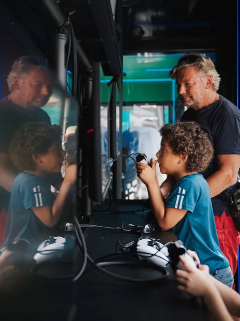 Ett barn och en vuxen som spelar tv-spel tillsammans på evenemanget