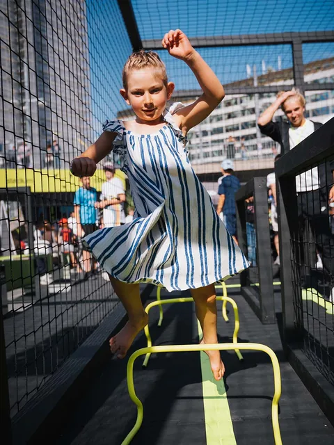 Ett barn som hoppar över ett gult hinder i en aktivitetsbana