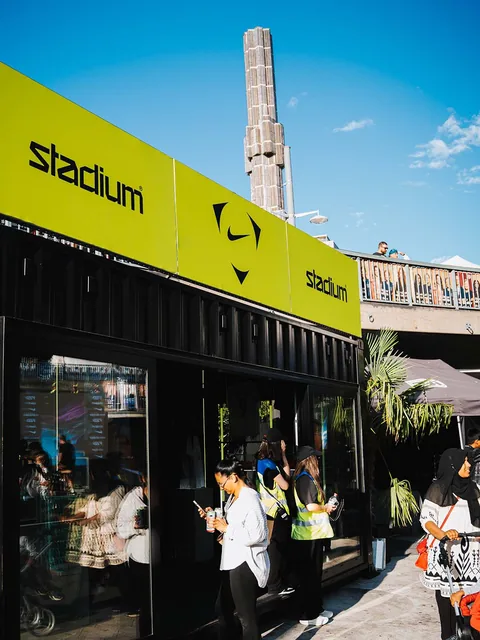 Besökare utanför Stadiums evenemangsyta under en gul skylt