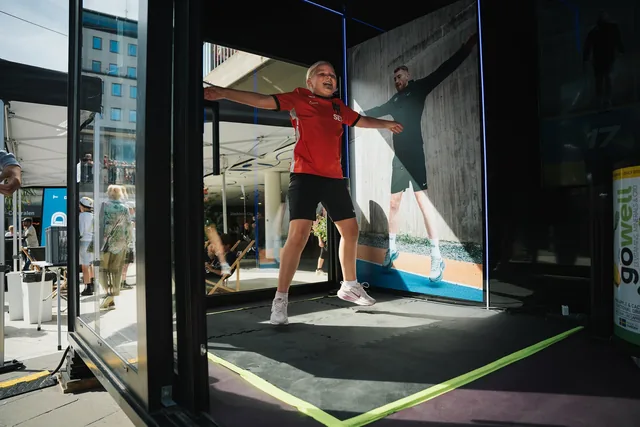 En deltagare som gör jumping jacks i ett aktivitetsbås på FUZED