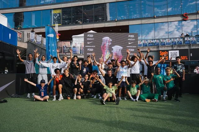 En grupp unga spelare och arrangörer som firar tillsammans på fotbollsplanen